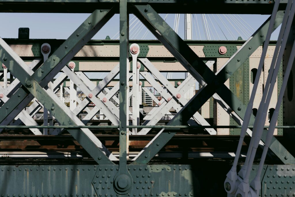 Close-up of a complex iron and steel bridge structure in an urban setting.